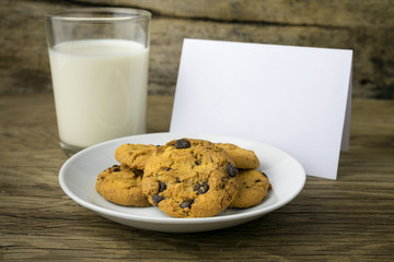 cookies and a glass with milk with a white note for santa