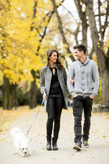 Fototapeta premium Young couple with dog in the autumn park