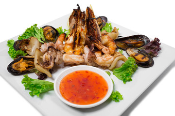 Grilled seafood platter with hot sauce.