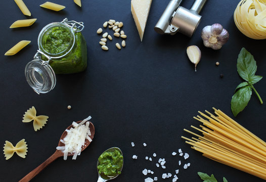 Pesto sauce ingredients and raw pasta on black chalkboard.  Food frame with free space in middle