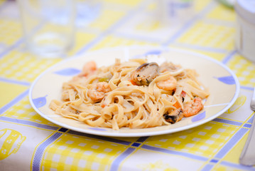 Plate with beautiful tasty seafood pasta standing on bright tablecloth