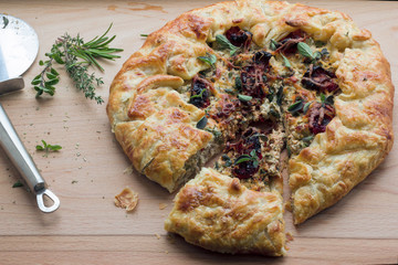Homemade rustic pie with feta cheese, sun-dried tomatoes and herbs