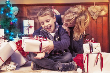 lovely little boy opens christmas gifts with her mother