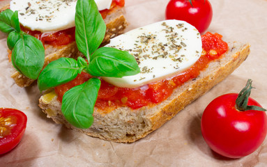 Fototapeta na wymiar Italian bruschetta with cherry tomatoes, mozzarella & fresh basil.