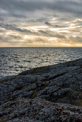Obraz premium Sunset by coast with cloudy sky and sunbeams lightning trough the clouds