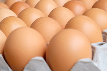 A dozen brown eggs in a carton on a wooden table
