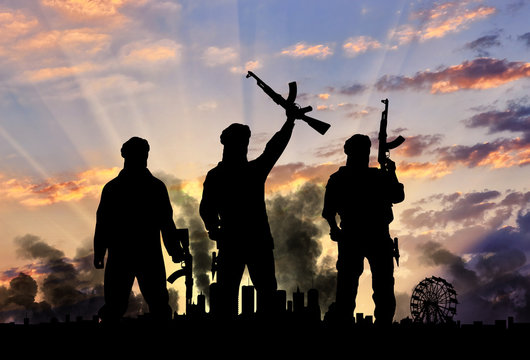 Silhouette of armed men and smoking cityscape during sunset