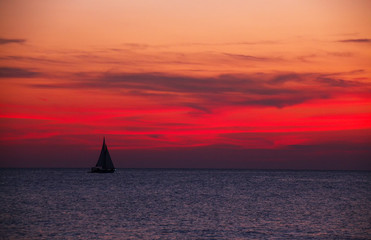 Sailboat on the ocean at bloody red sunset