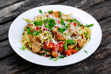 Italian Chicken Breast spaghetti with red pepper, Parmesan cheese and wild rocket  lives. on old wooden table