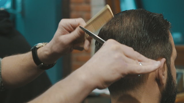 Barber cuts the hair of the client with scissors