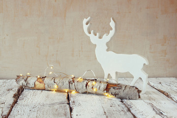 old tree log with fairy christmas lights and reindeer on wooden table.selective focus

