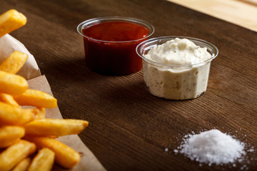 Fresh fried french fries with ketchup on wooden background