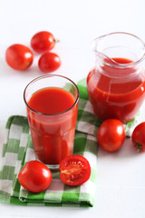 Fresh red tomatoes in basket and tomato juice in glass and jug o