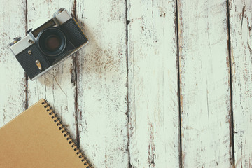 top view image of blank notebook, cup of coffee and old camera
