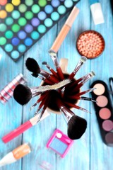 Makeup brushes and cosmetics on blue wooden table