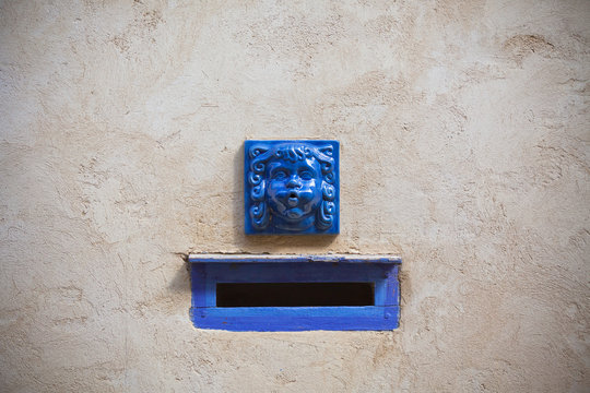 Plaster wall with blue decorative letter slot mailbox