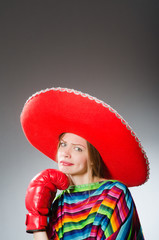 Girl in mexican vivid poncho and box gloves against gray