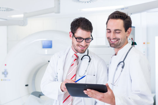 Ärzte diskutieren Bilder von Röntgen Scan aus Tomograph und stehen dabei vor Röntgengerät im Krankenhaus