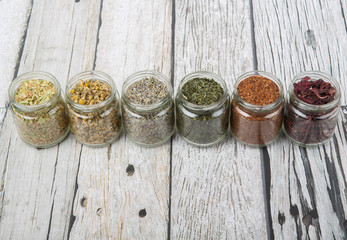Dried herbal tea lavender, chamomile, linden flower, hibiscus, rooibos, Japanese green tea in mason jar over wooden background