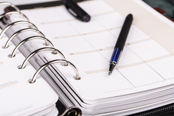 Personal organizer or planner with pen on white background