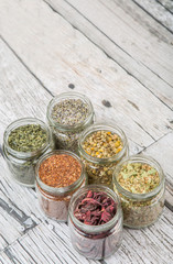 Dried herbal tea lavender, chamomile, linden flower, hibiscus, rooibos, Japanese green tea in mason jar over wooden background
