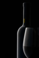 red wine glass and bottle on black