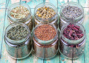 Dried herbal tea lavender, chamomile, linden flower, hibiscus, rooibos, Japanese green tea in mason jar over wooden background