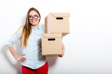 Happy woman moving into house carrying boxes.