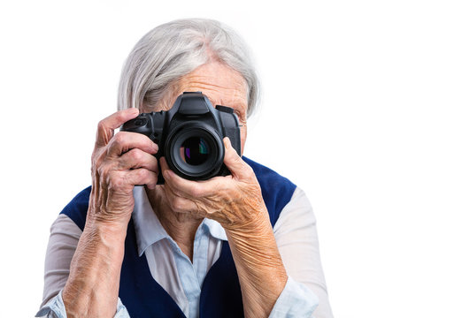 Senior woman shooting with a digital camera over white background