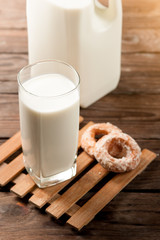 Glass of milk with doughnut on wood