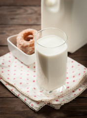 Glass of milk with doughnut on wood