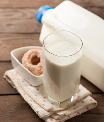 Glass of milk with doughnut on wood