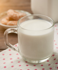 Glass of milk with doughnut on wood
