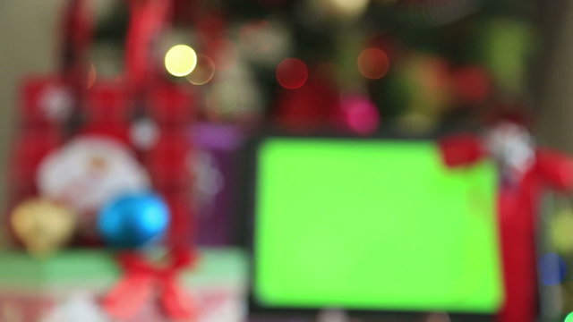 Green screen digital tablet with gift box and christmas tree lights background