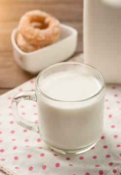 Glass of milk with doughnut on wood