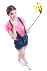 Young woman taking picture with smartphone selfie stick