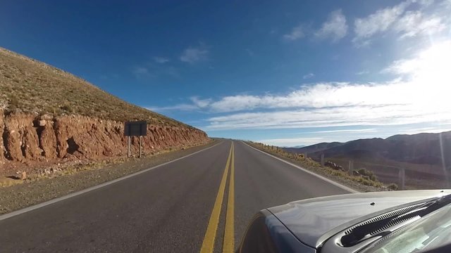Front view of car driving on the famous paved road Route 40 parallel to the Andes against a blue sky and going towards the Ischigualasto National Park, San Juan Province. Argentina 2014