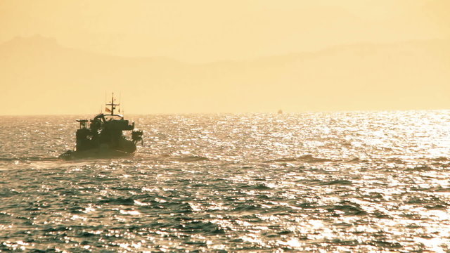 Fishing boat crosses the sea at afternoon,long shot.