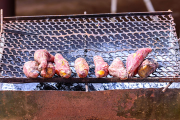 Fresh yam grilling on metal grille.