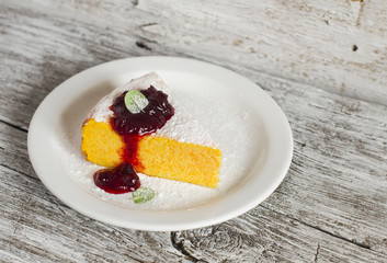 Cottage cheese and pumpkin casserole with  berry sauce on a white plate on a light wooden board