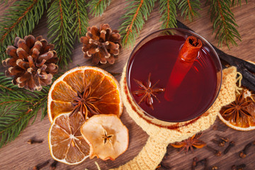 Glass of mulled wine wrapped scarf, spices and spruce branches