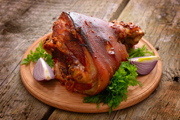 Baked Eisbein with wegetables on wooden board.