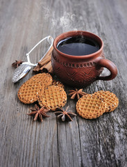 A cup of hot tea with cookies on a rustic wooden background