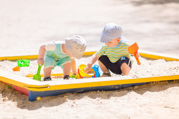 Fototapeta na wymiar Two baby boys playing with sand