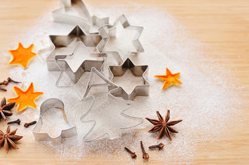 Metal Christmas Cookie Cutters in Freshly Sifted Flour on Wooden Chopping Board