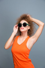Attractive curly female in sunglasses posing and biting bottom lip