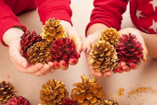Children holding painted pine cones