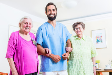 Altenpfleger mit zwei Seniorinnen im Seniorenheim