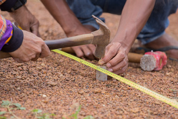 Worker working with measuring tape, hammer and nail