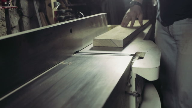 joiner processing the workpiece of wooden plank by jointing machine